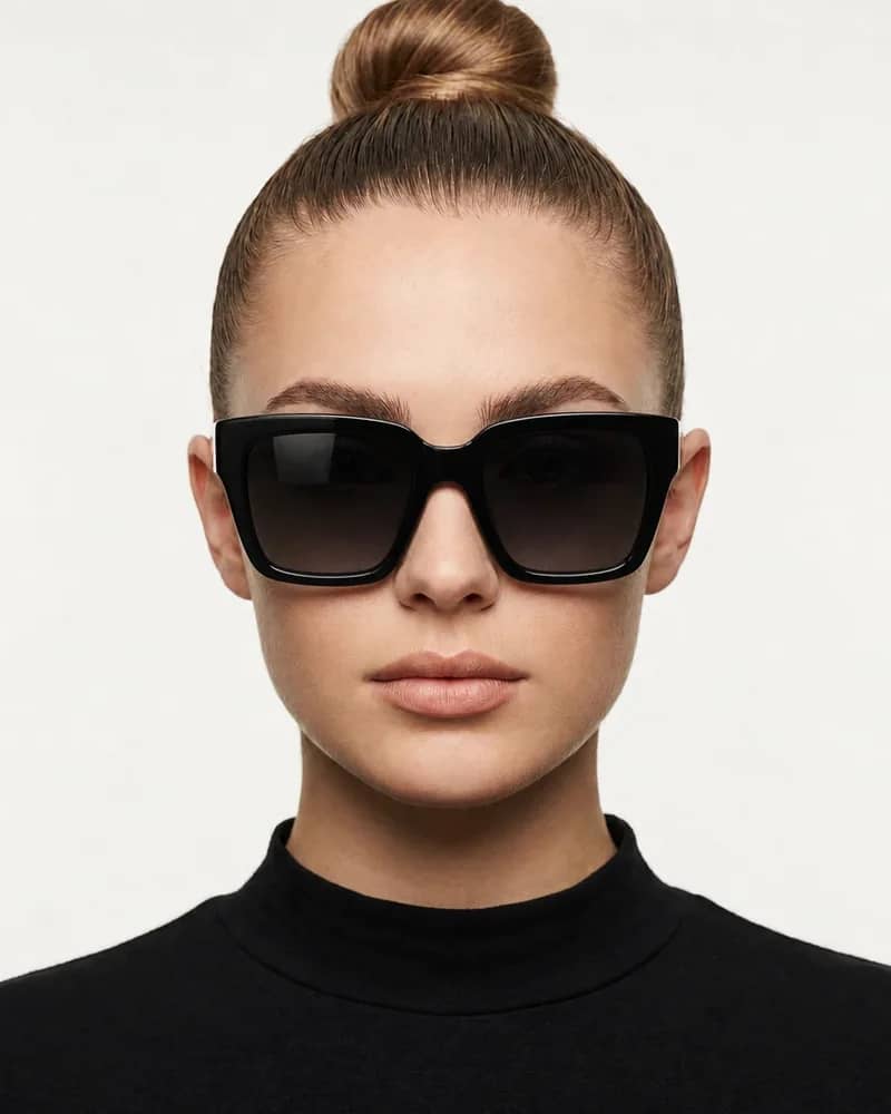 Same woman wearing oversized black square sunglasses with dark gradient lenses