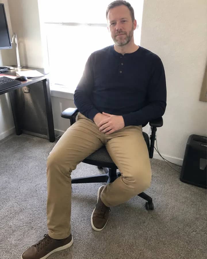 White man seated with crossed legs and harsh window backlight in a poor AI outfit try-on source photo