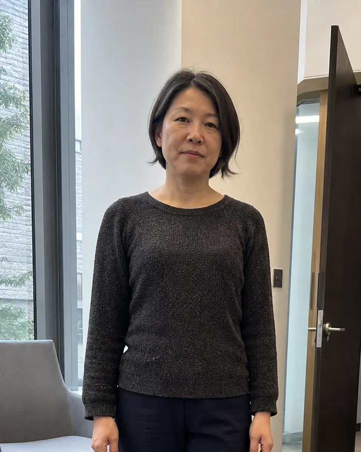 Woman wearing a charcoal knit top and navy trousers before an AI workwear try-on