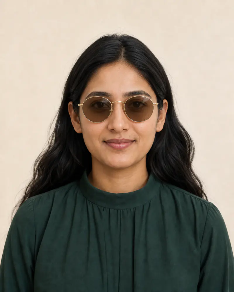 Same woman wearing thin gold round sunglasses with warm-brown lenses